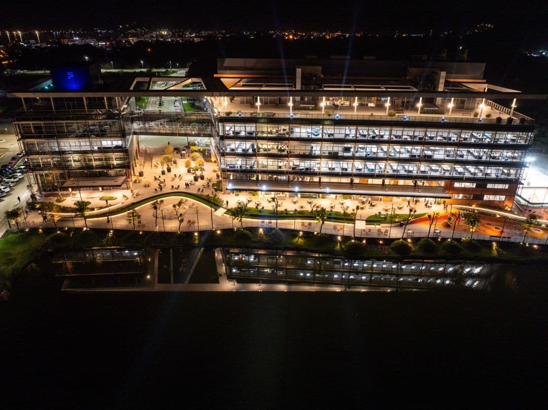 Sapiens Parque iluminado à noite com reflexo no lago